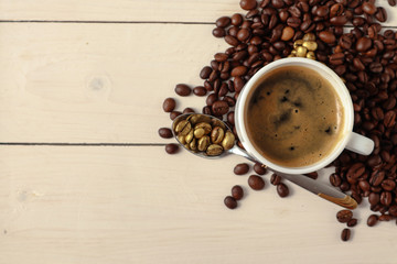 Cup with tasty coffee and roasted grains on wooden table