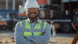 © Gorodenkoff - Portrait of Contractor / Investor / Architectural Engineer Wearing Hard Hat and Safety Vest Standing on a Commercial Building Construction Site, Crosses Arms Confidently. In Background Crane Machinery