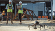 © Gorodenkoff - Two Specialists Use Drone on Construction Site. Architectural Engineer, Safety Engineering Inspector Fly Drone on Commercial Building Construction Site Controlling Design and Quality. Focus on Drone