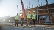 © Gorodenkoff - Diverse Team of Specialists Inspect Commercial, Industrial Building Construction Site. Real Estate Project with Civil Engineer, Investor and Worker. In the Background Crane, Skyscraper Formwork Frames