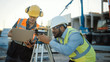 © Gorodenkoff - Inside of the Commercial / Industrial Building Construction Site: Engineer Surveyor Takes Measures with Theodolite, Using Digital Tablet Computer. In Background Skyscraper Formwork Frames and Crane