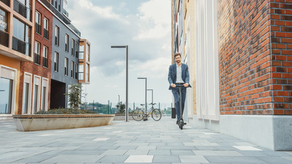 Young Businessman in a Suit Riding to Work on an Electric Scooter. Modern Entrepreneur Uses Contemporary Ecological Transport to Go on an Office Meeting.