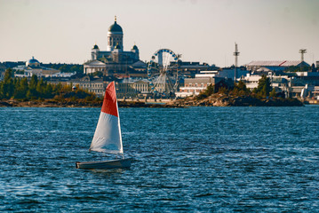 Sailing boat front of Helsinki Finland capital. Landscape with Finnish gulf the metropoly in background with landmarks such cathedral church and ferris wheel. Tourist spot. 