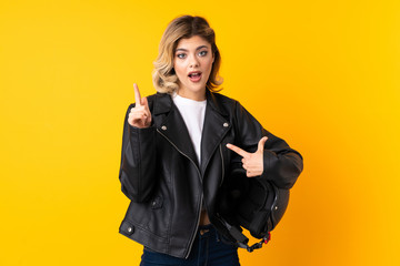 Wall Mural - Teenager woman holding a motorcycle helmet isolated on yellow background with surprise facial expression