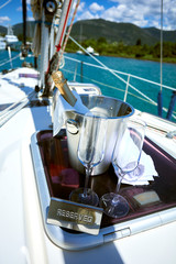 Wall Mural - Romantic luxury evening on cruise yacht with champagne setting. Empty glasses and bottle with champagne and tropical sunset with sea background