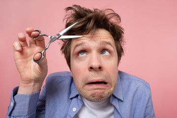 man trying to make a hairstyle by himself with scissors being on quarantine