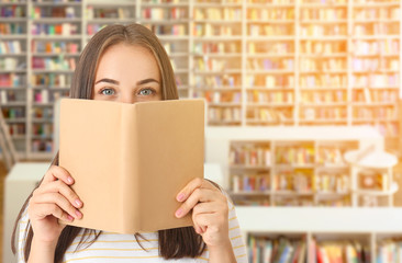 Wall Mural - Portrait of beautiful woman with book in modern library