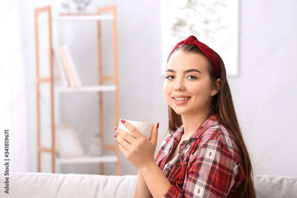 Beautiful young woman drinking tea at home