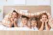 © Pixel-Shot - Happy family lying in bed at home