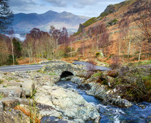 A View Of The Traditional Stone Ashness Bridge In Borrowdale Showing The Water Flowing Down To Derwent Water Keswick. 