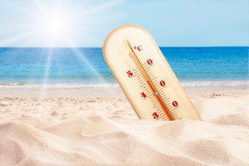 Weather thermometer with high temperature on sandy beach near sea