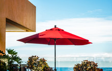 Red Umbrella On A Rooftop Patio, Tropical Sky With An Ocean View On Horizon
