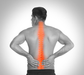 Wall Mural - Man suffering from pain in spine on light background. Black and white effect