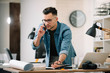 © JustLife - Businessman in office. Handsome man talking on phone at work