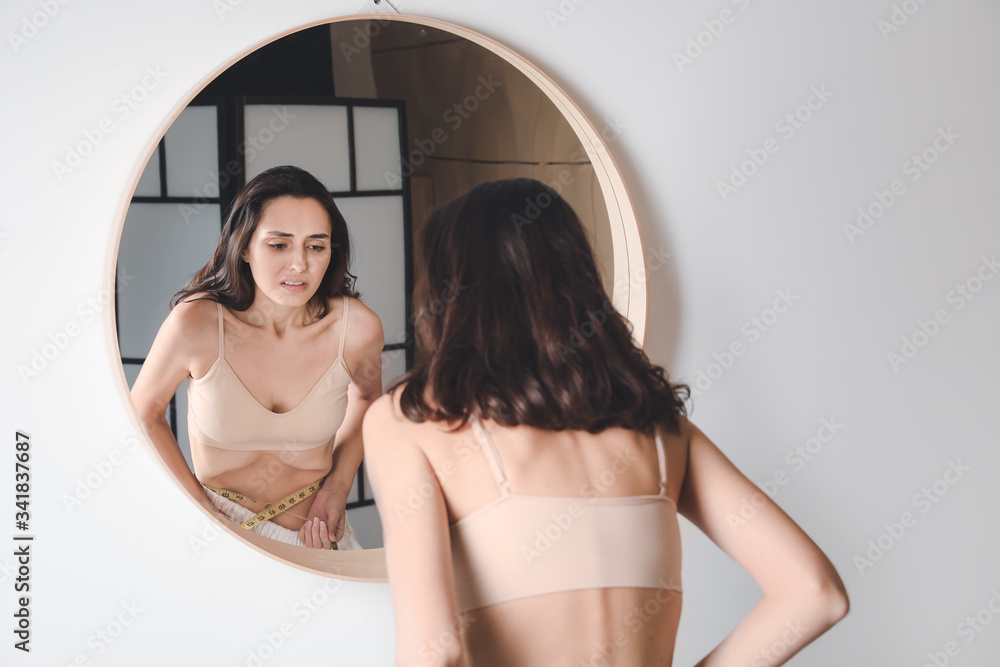 Young woman with anorexia near mirror at home