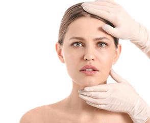 Wall Mural - Plastic surgeon examining face of young woman on white background