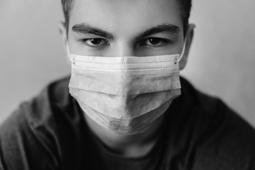 Wall Mural - Close - up portrait of a man with a gaze and in wearing medical mask. Protection against virus, infection, exhaust and industrial emissions. Monochrome studio shot.