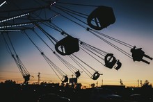 Illuminated Silhouette Chain Swing Ride Against Sky During Sunset