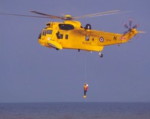 Man Hanging From Rescue Helicopter Flying Over Sea