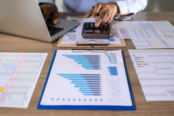Wall Mural - Man Usingcalculator with money stack Financial Report- Business Accounting Concept accounting money with statistics graphs