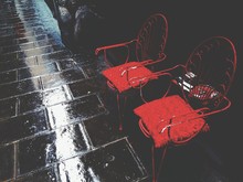 High Angle View Of Red Chairs On Wet Sidewalk