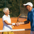 © Microgen - Tennis Instructor with Senior Woman in her 60s Handshaking after Having a Tennis Lesson on Clay Court.