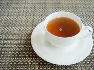 White cup of hot tea. Isolated on wood mat background.