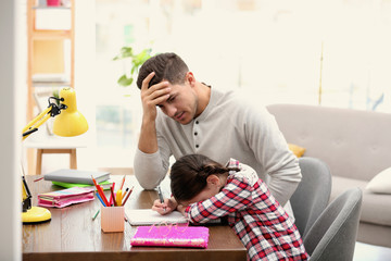 Poster - Upset father and daughter doing homework together at table indoors