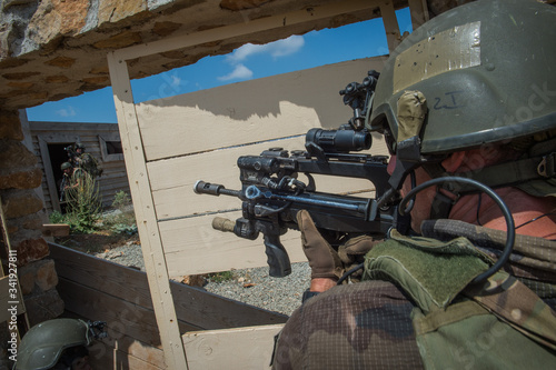 Fotomural a man aiming in the scope of his weapon during a simulation of conflict between
