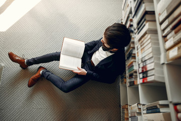 Wall Mural - Man in a library. Guy in a black suit. Student with a books.