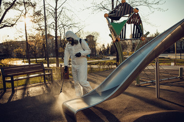 Wall Mural - Cleaning and Disinfection on the playground in the sity complex amid the coronavirus epidemic Teams for disinfection efforts Infection prevention and control of epidemic Protective suit and mask