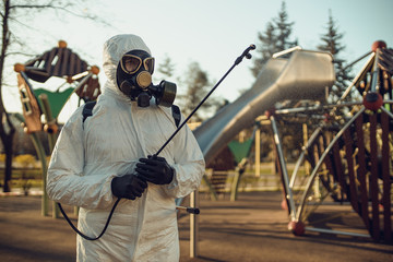 Wall Mural - Cleaning and Disinfection on the playground in the sity complex amid the coronavirus epidemic Teams for disinfection efforts Infection prevention and control of epidemic Protective suit and mask