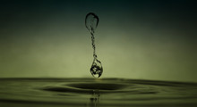 Close-up Of Drop Falling In Water Against Gray Background