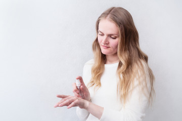 Caucasian woman uses hand sanitizer on the light background with copy space. quarantine, coronavirus, covid-19