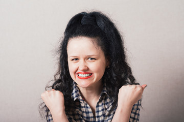 happy woman celebrating and dancing of joy winning. studio shot over gray background