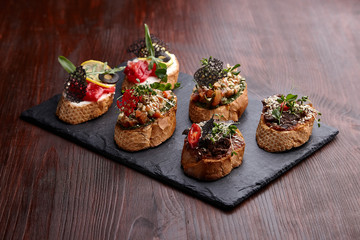 Appetizing bruschettas on a stone stand on a wooden table.