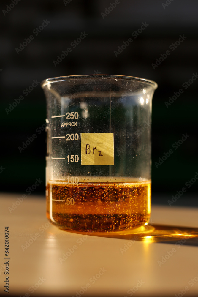 The formation of red liquid bromine in a beaker with a volume of 250 milliliters. - obrazy, fototapety, plakaty 