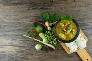 Green curry (Kaeng kheiyw hwan) with Thai food for steamed rice or rice noodles. chicken green curry is thai food very popular on dark wooden background. top view