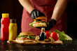 © melnyksergey - The chef prepares a burger, a hamburger on a background with ingredients. Delicious and fast food. A menu, a cafe, fast food, catering, gastronomy