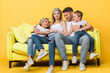 © LIGHTFIELD STUDIOS - smiling pregnant mother, father and kids sitting on sofa on yellow