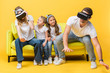 © LIGHTFIELD STUDIOS - laughing children sitting on sofa with parents in virtual reality headsets on yellow