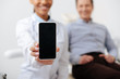 © LIGHTFIELD STUDIOS - selective focus of cheerful african american dentist holding smartphone with blank screen near happy patient