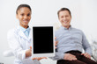 © LIGHTFIELD STUDIOS - selective focus of happy patient near cheerful african american dentist holding digital tablet with blank screen