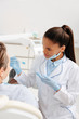 © LIGHTFIELD STUDIOS - selective focus of african american dentist in latex gloves pointing with hand at toothbrush near patient