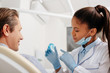 © LIGHTFIELD STUDIOS - selective focus of african american dentist in latex gloves pointing with finger at retainer near happy patient