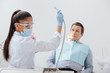 © LIGHTFIELD STUDIOS - african american dentist in medical mask and face shield holding dental instrument near man