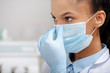 © LIGHTFIELD STUDIOS - african american dentist touching medical mask in clinic