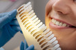 © LIGHTFIELD STUDIOS - cropped view of dentist in latex gloves holding teeth palette near smiling man