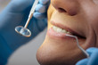 © LIGHTFIELD STUDIOS - cropped view of dentist in latex gloves holding dental instruments near happy man