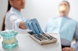 © LIGHTFIELD STUDIOS - selective focus of african american dentist in latex glove taking dental instrument near patient